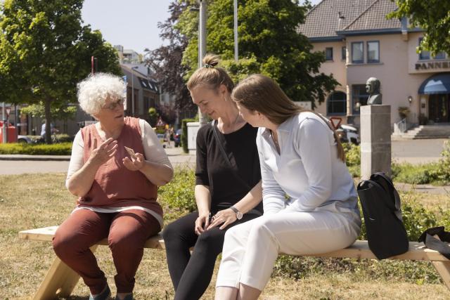 trois personnes discutent assises sur un banc